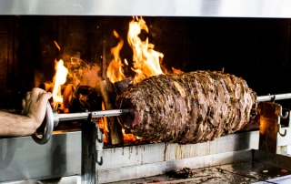 Turkish doner kebab slow roasting over wood fire oven.